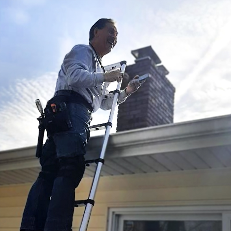 Steve on a ladder inspecting a roof during a home inspection