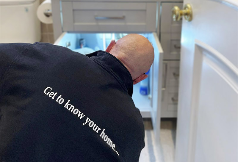 Walt checking under a sink while preforming home inception services